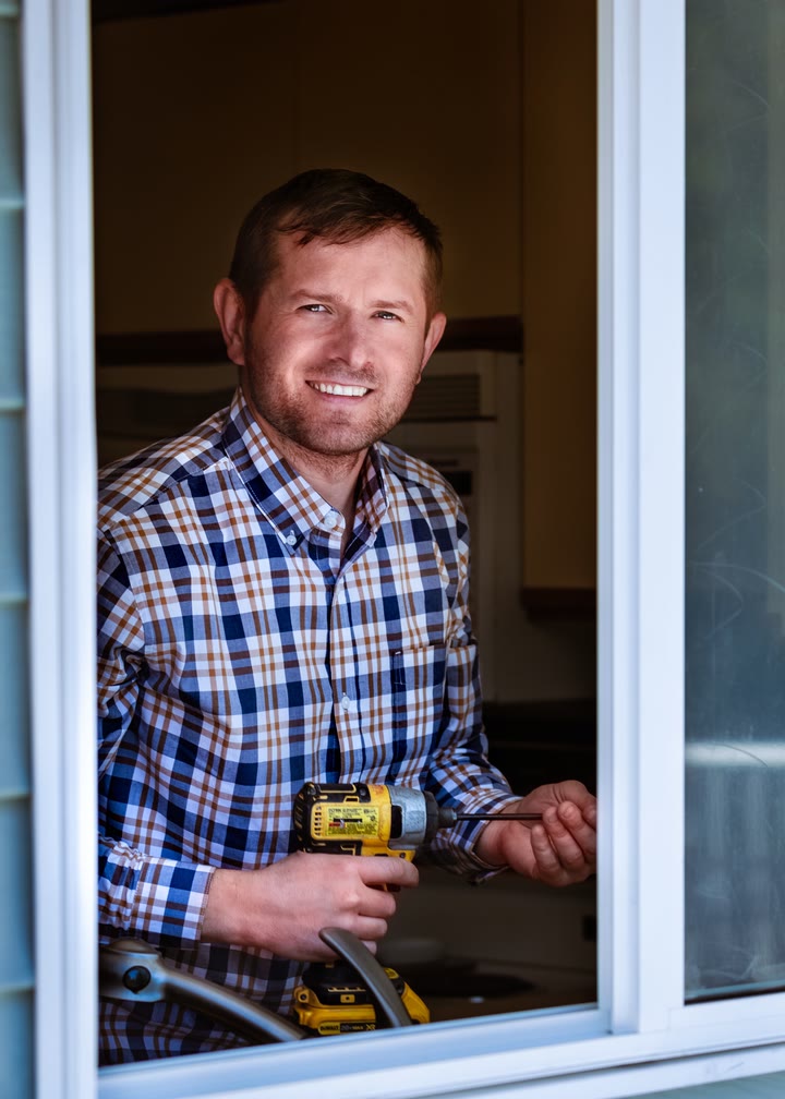 A smiling contractor fitting a new window